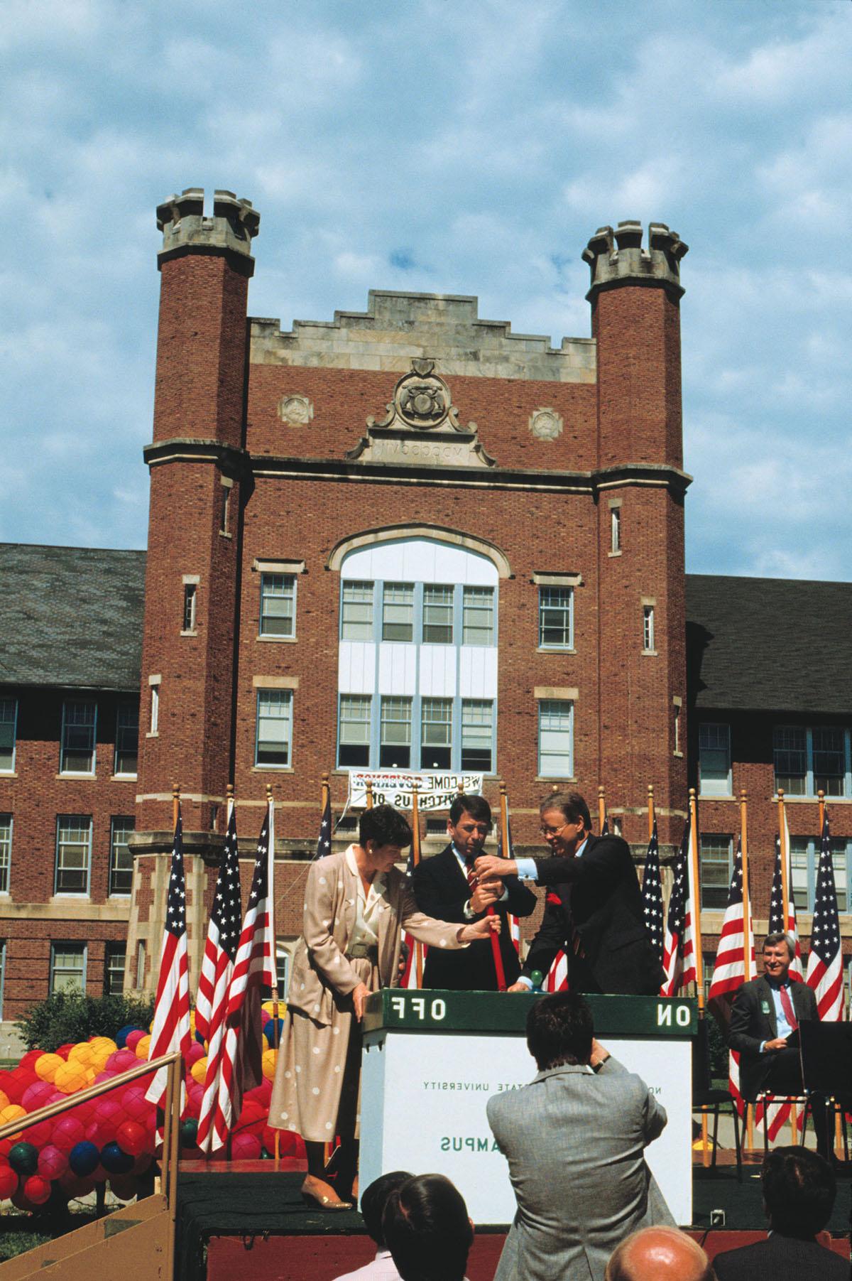威尼斯人在线校长迪恩·哈伯德(左)拉开仪式的开关, “电子校园”于八月六日正式启用. 1987年8月18日，与州长. 约翰·阿什克罗夫特和密苏里州高等教育专员谢拉·艾瑞. 威尼斯人在线是全国第一所拥有校园计算机系统的公立大学.